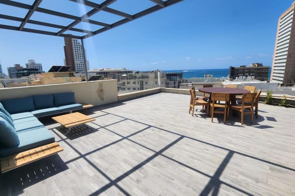 eine Terrasse mit einem Tisch und Stühlen auf dem Dach in der Unterkunft Penthouse Sea View in Ben Yehuda by HolyGuest in Tel Aviv