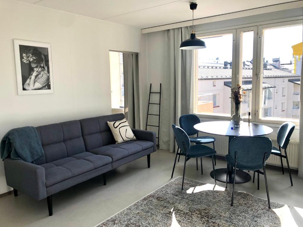 a living room with a couch and a table and chairs at Top floor one bedroom apartment with balcony in Helsinki