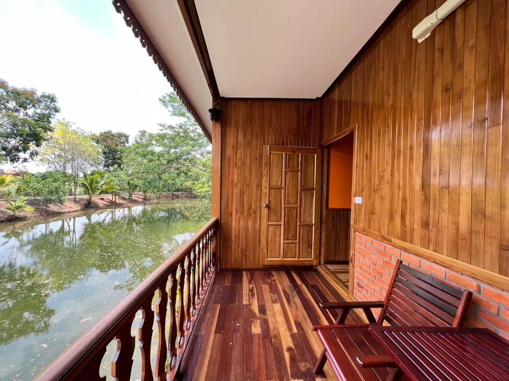 een houten balkon met een bank en een rivier bij ชานไม้ รีสอร์ท 