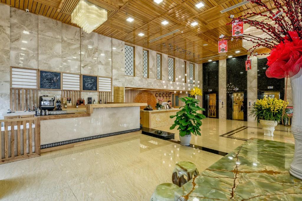 A spacious marble-floored lobby with a reception counter, drinks station, elevator and festive floral decorations.