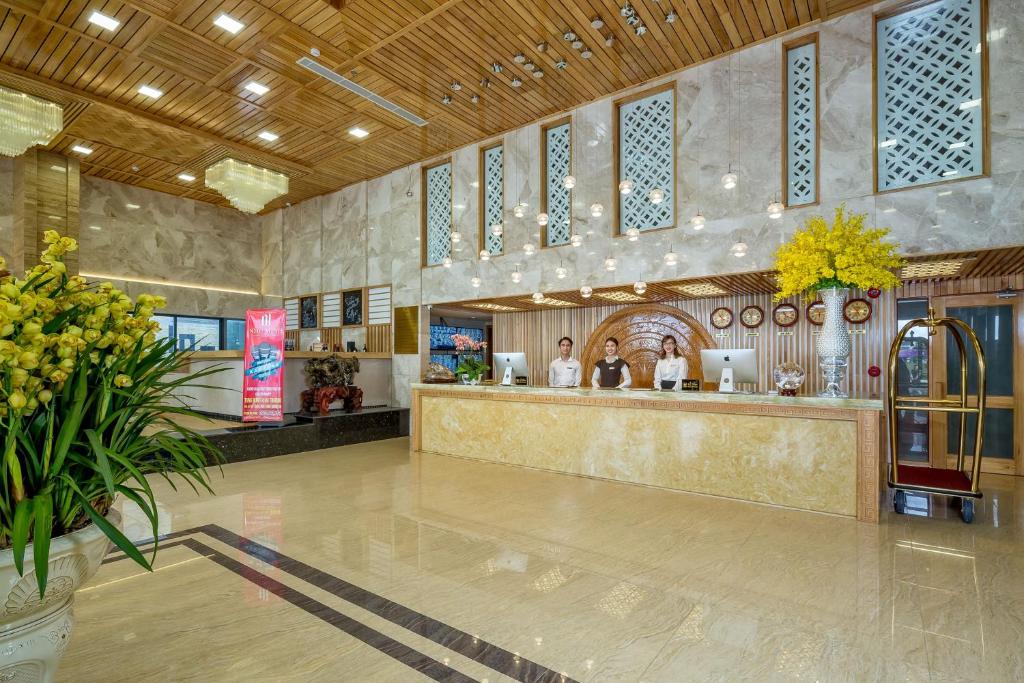 A spacious lobby reception with a long marble-front desk and wood ceiling.