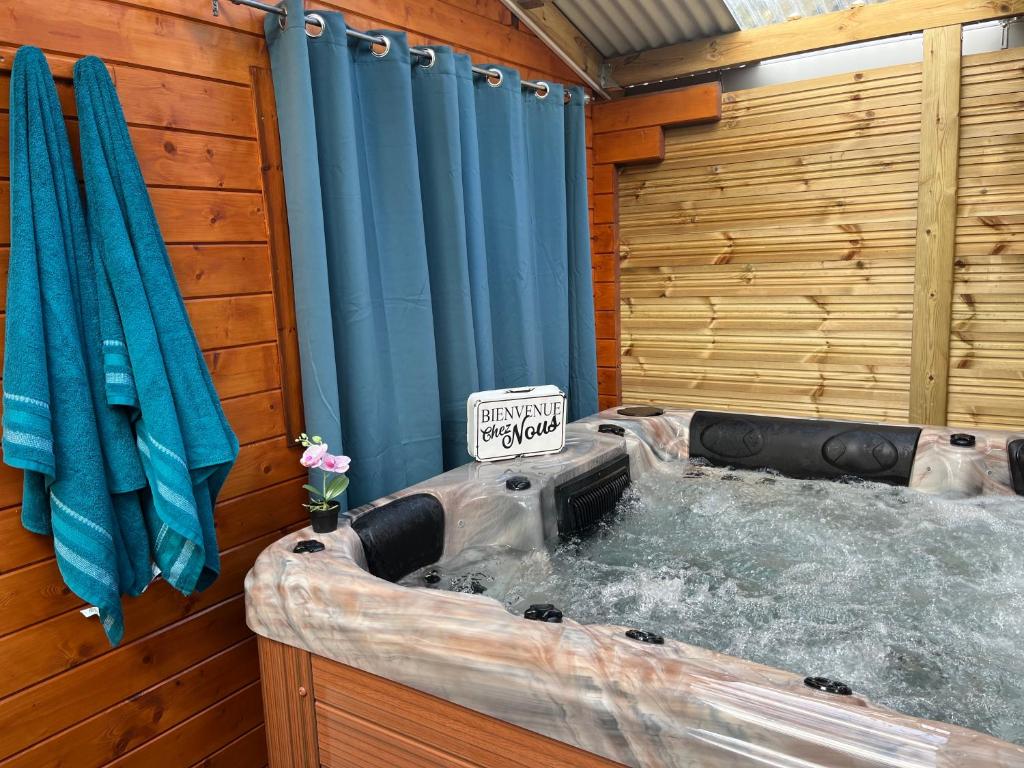 bañera de hidromasaje en una habitación con cortina de ducha azul en Les Chalets de Marie & Stéph - Jacuzzi SPA privatif sans vis à vis , vue mer en Saint-Denis