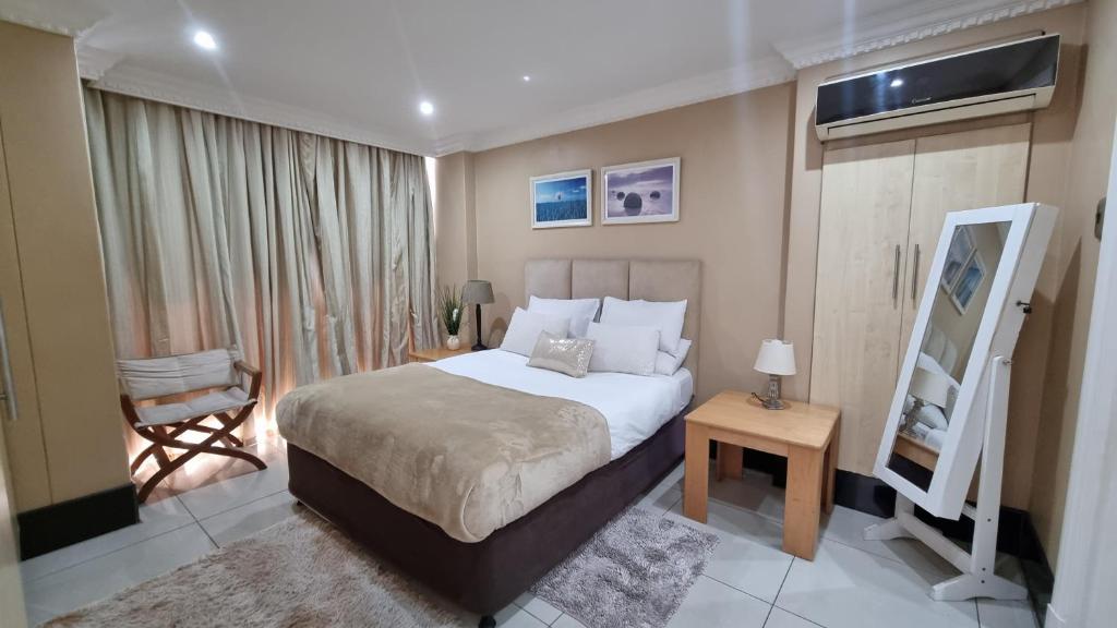 a bedroom with a bed and a chair and a mirror at Accommodation Front - Dazzling 4 Sleeper near Ushaka Marine World in Durban