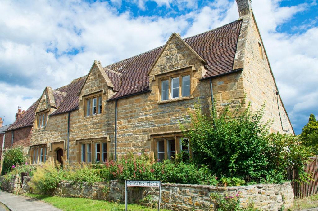 an old stone house with a sign in front of it at The Gables in Cow Honeybourne