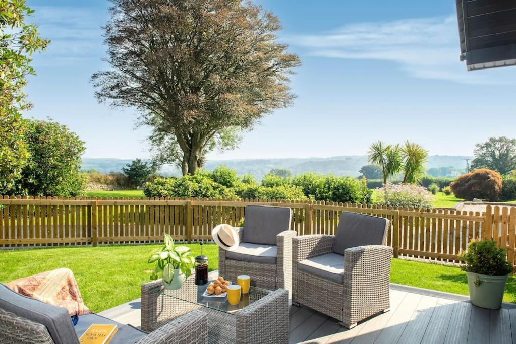 a patio with two chairs and a table at Luxury Country Cottage, near Tavistock. in Tavistock