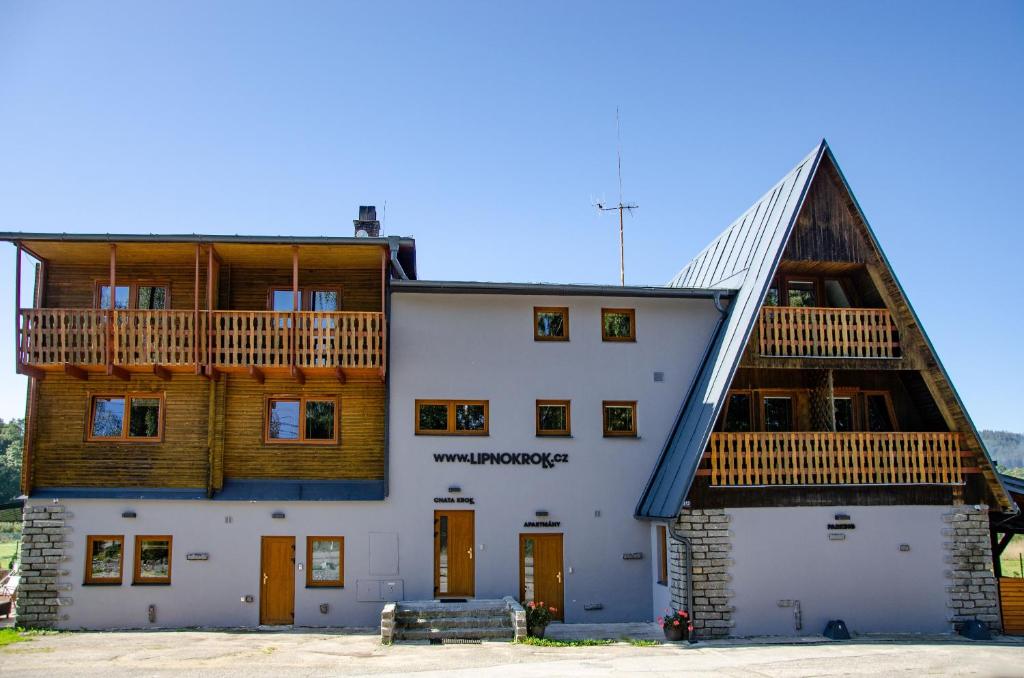 ein großes weißes Gebäude mit einem Holzdach in der Unterkunft KROK in Horní Planá