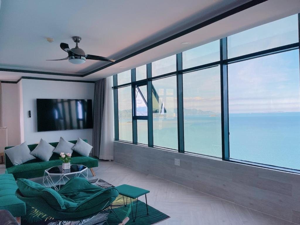 - un salon avec un canapé vert et une grande fenêtre dans l'établissement Gold Beach Nha Trang Apartment, à Nha Trang