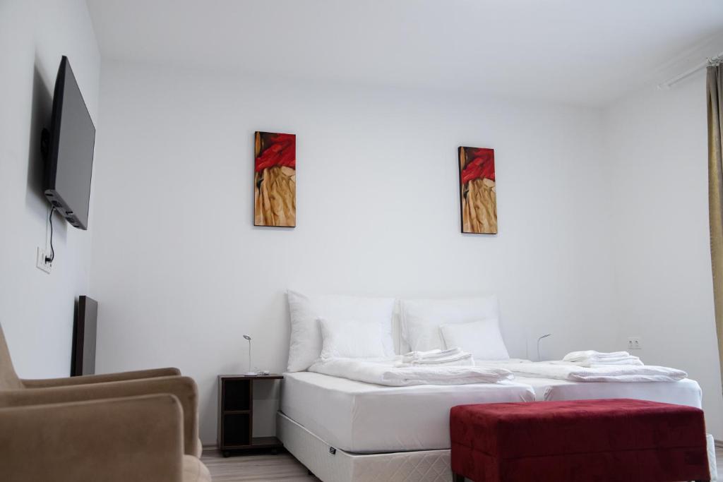 Rozmaring Apartmanház في موراهالوم: غرفة بيضاء بسريرين وكرسي