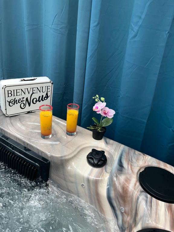 dos vasos de zumo de naranja y flores en una bañera de hidromasaje en Les chalets de Marie et Stéph - Jacuzzi SPA Privatif sans vis à vis , vue mer, en Saint-Denis