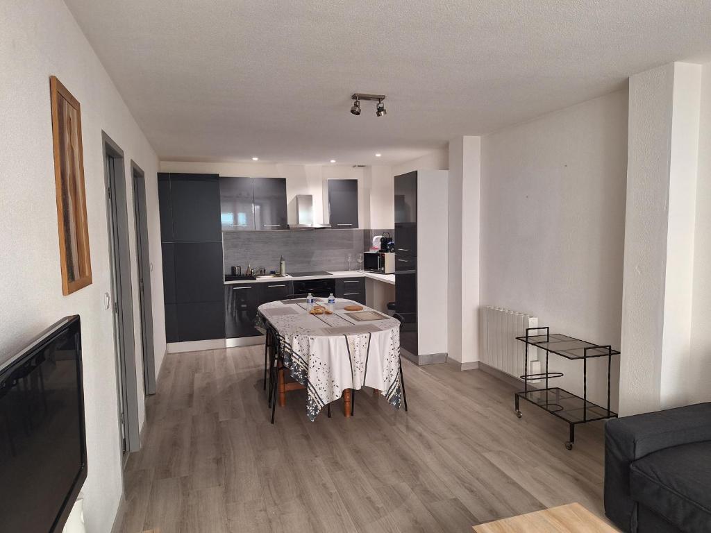 a living room with a table and a kitchen at Au cœur de Caillassou in Villemur-sur-Tarn