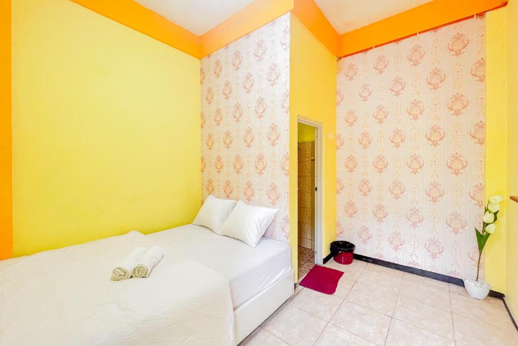 - une chambre avec 2 lits et un mur jaune dans l'établissement Sion Homestay Mitra RedDoorz near Terminal Kertajaya Mojokerto, 