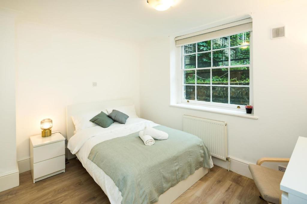 a white bedroom with a bed and a window at Cozy 1 bedroom at Notting Hill in London
