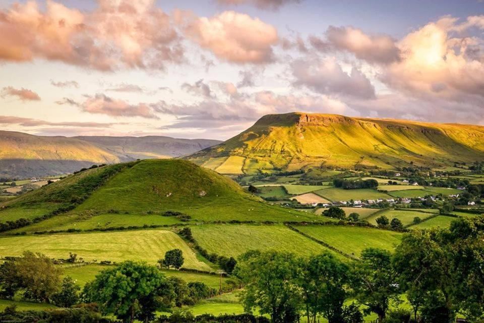 a view of a mountain with green fields and trees at Number 19 Heart Of The Glens in Cushendall