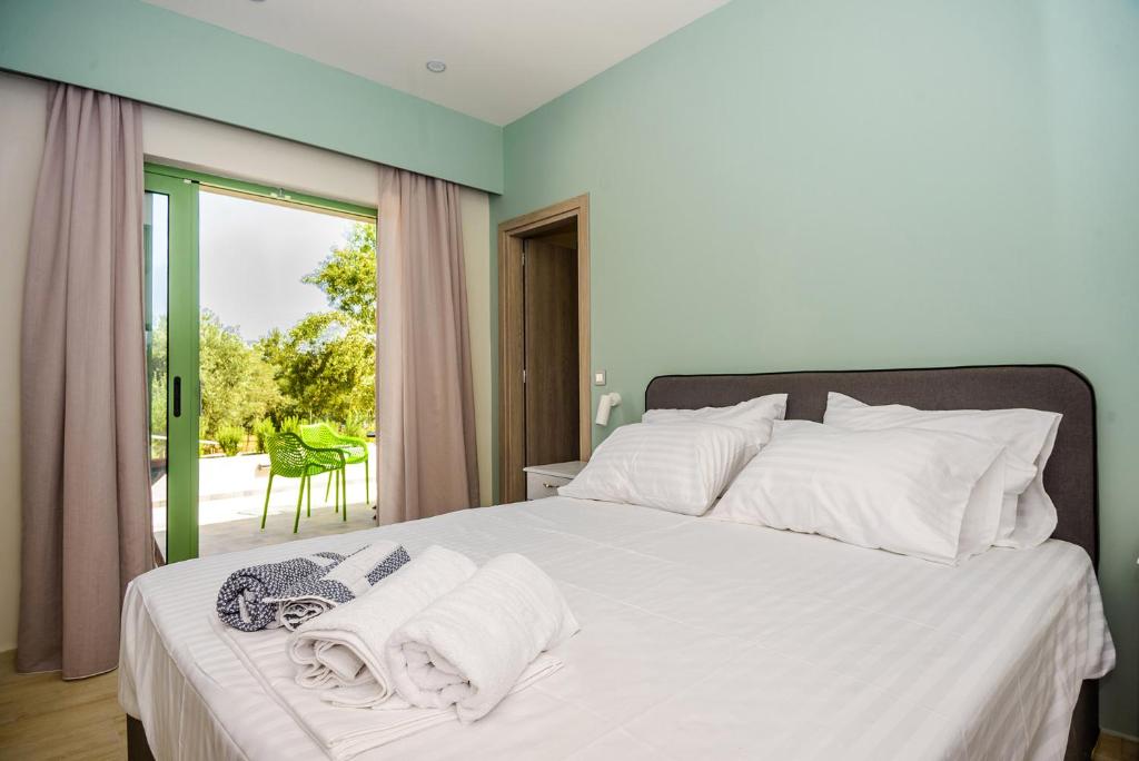 a bedroom with a bed with white sheets and a window at HELEN aparment in Argostoli