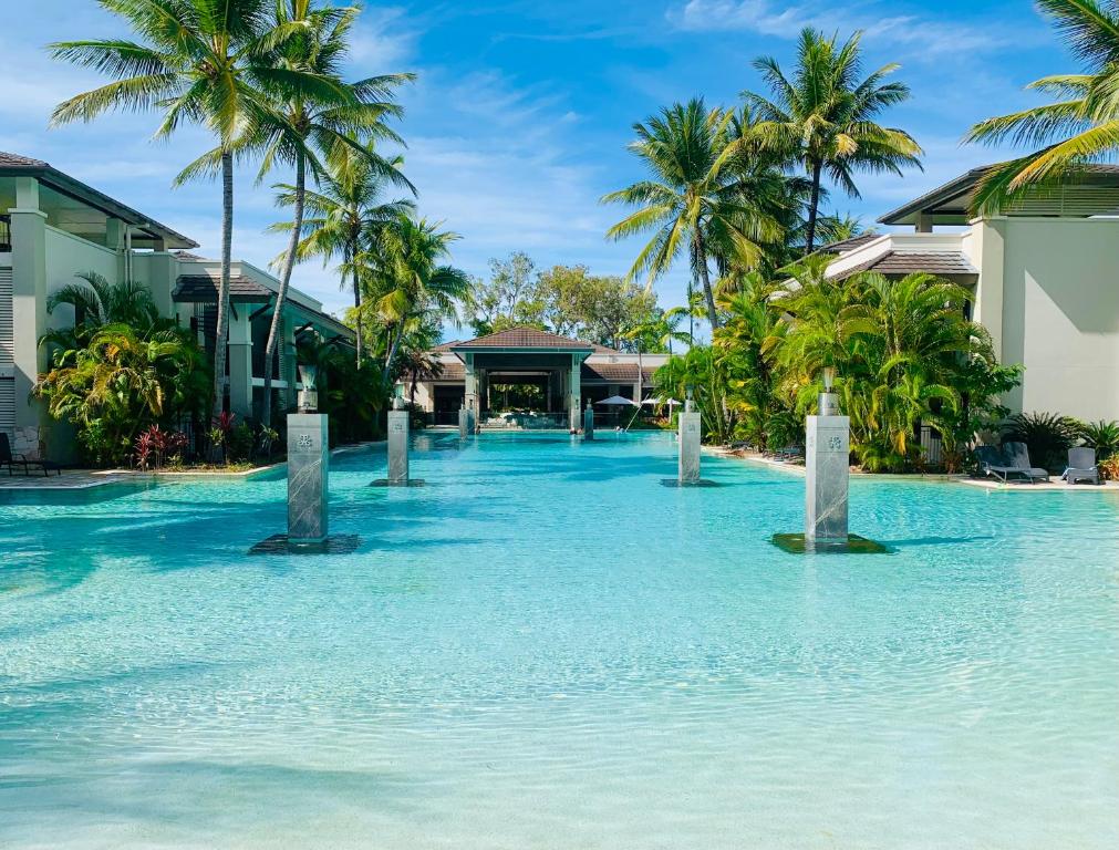 a pool in the middle of a resort with palm trees at Paradise Escape - Poolside Ground Floor - Sea Temple Resort and Spa in Port Douglas