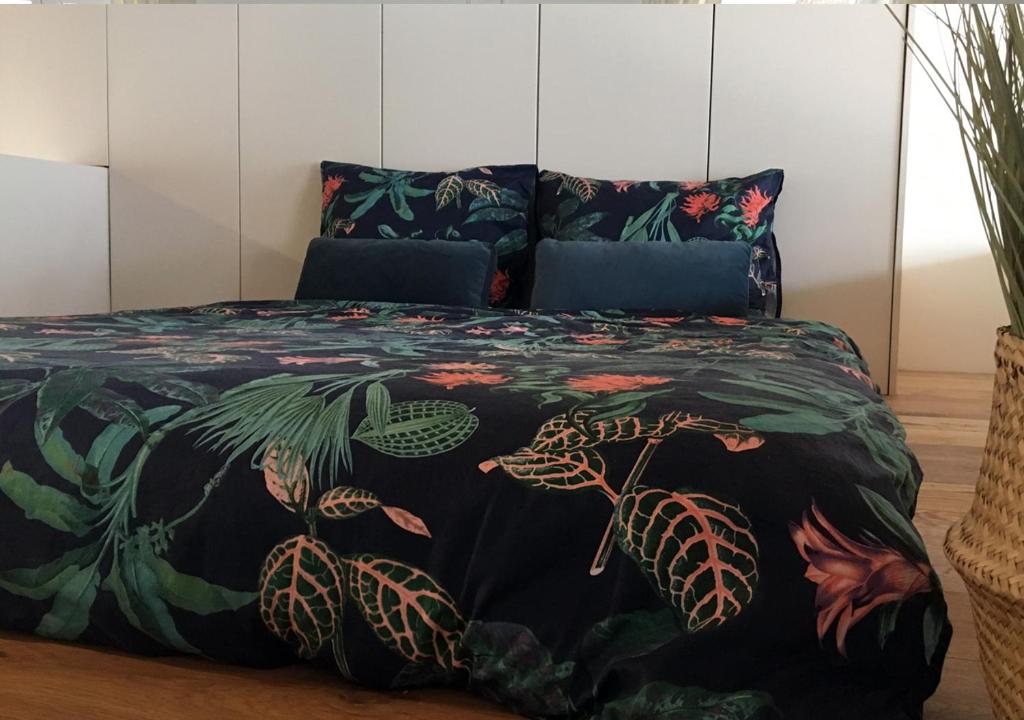 Una cama con una colcha negra con plantas. en Antwerpen perfect location, en Amberes