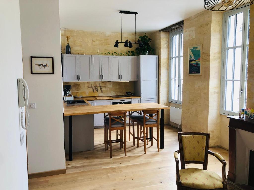 uma cozinha com uma mesa de madeira e cadeiras em La Pomme d'Or em Bordéus