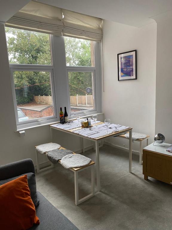 uma sala de estar com uma mesa e duas janelas em G-Floor Flat with 2 beds, 2 bathrooms, slips 4-6 em West Bridgford
