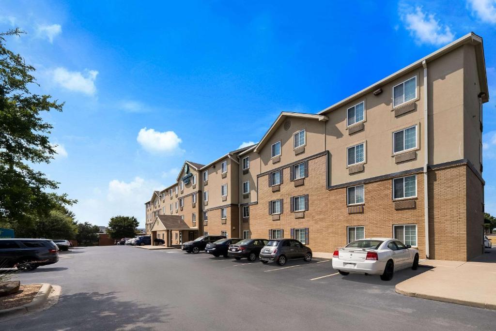 WoodSpring Suites Fort Worth Fossil Creek في فورت وورث: مبنى كبير به سيارات تقف في موقف للسيارات