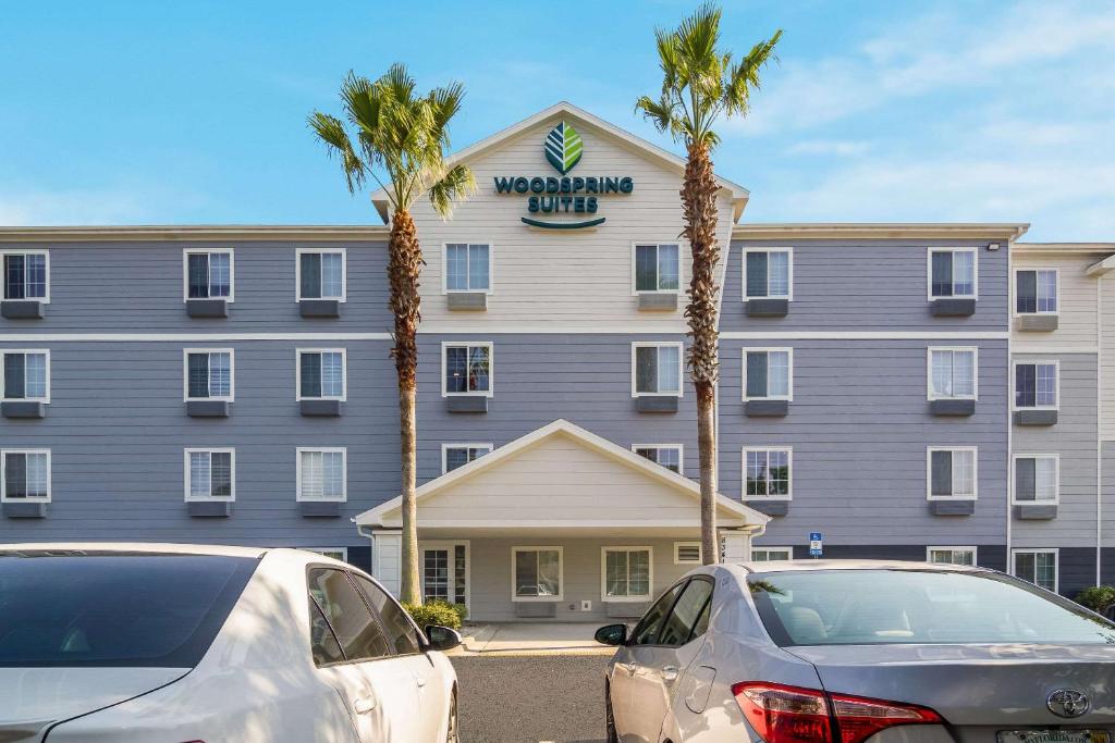 ジャクソンビルにあるWoodSpring Suites Jacksonville I-295 Eastのホテルの前に2台の車が停まっています