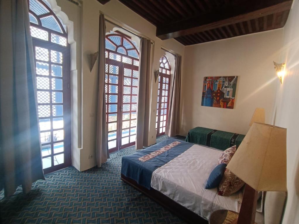 chez youssef في فاس: غرفة نوم بسرير ونوافذ كبيرة