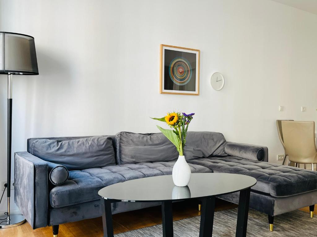 Modern Apartment in Mitte في برلين: غرفة معيشة مع أريكة وطاولة مع إناء من الزهور