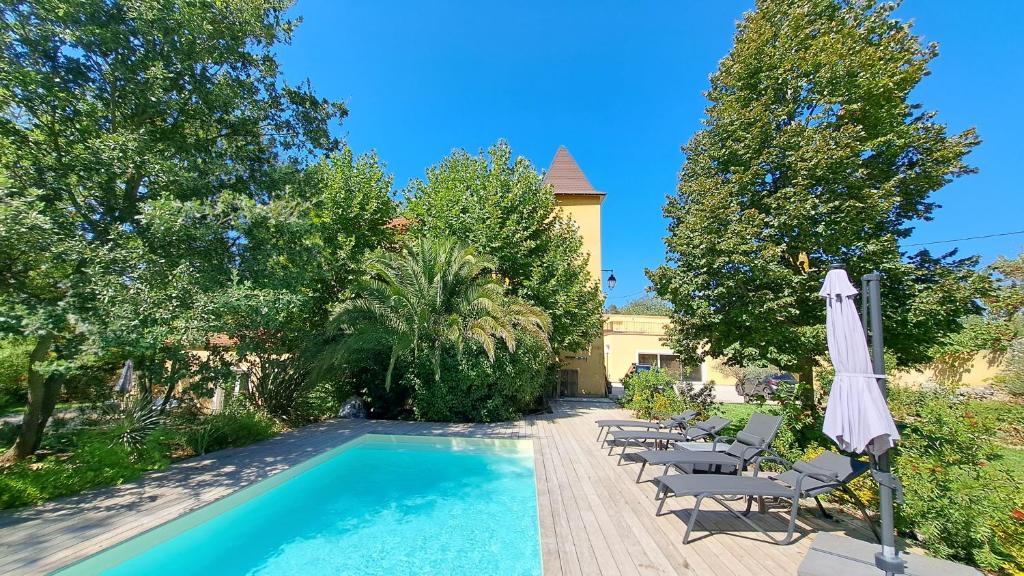a swimming pool with chairs and an umbrella at Les chambres du Chateau de Fenestrelle in Aubagne