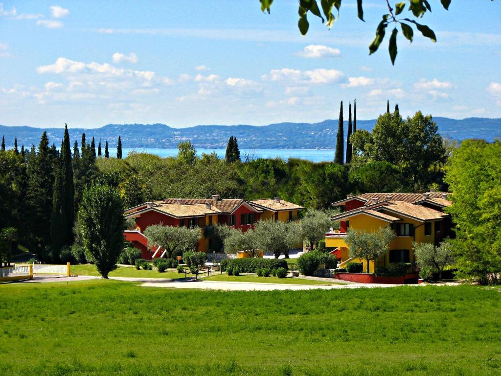 un parque con casas, árboles y un lago en Poiano Garda Resort Appartamenti, en Garda