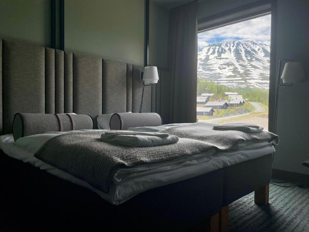a bedroom with a bed with a view of a snow covered mountain at Gausta View Lodge in Gaustablikk
