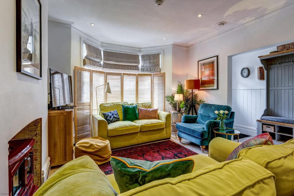 uma sala de estar com um sofá amarelo e cadeiras em The Oxford Artist's House em Oxford