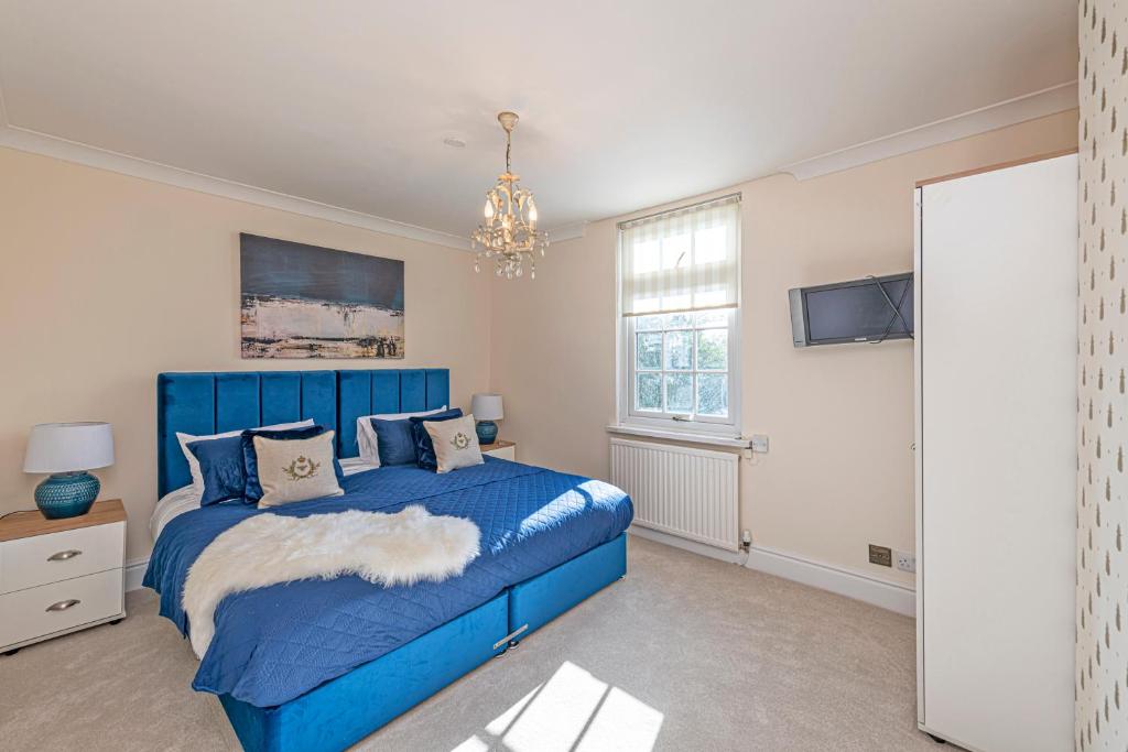 a bedroom with a blue bed and a chandelier at Bay Cottage in Malpas