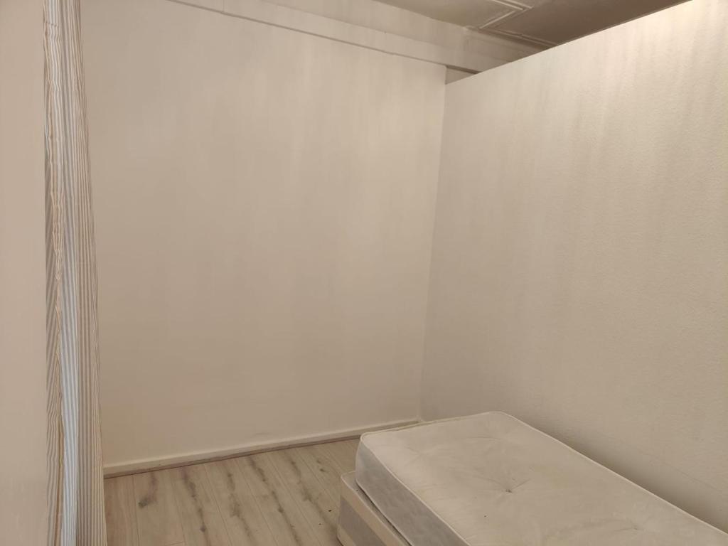 una habitación vacía con una pared blanca y un banco en Millais Road en Londres