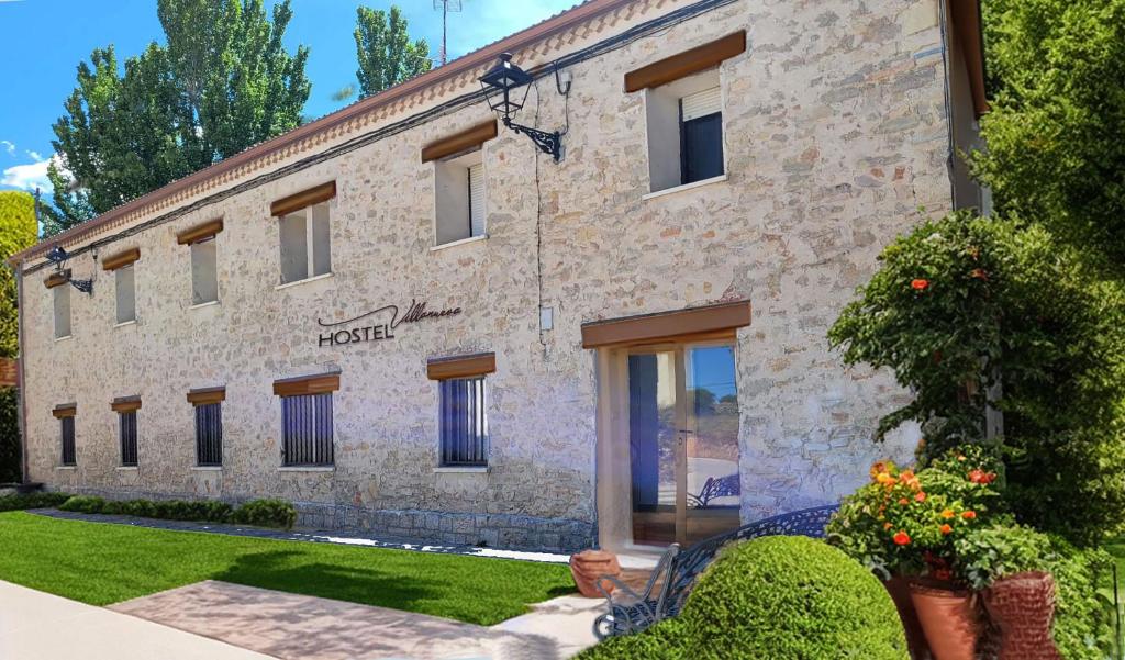 un gran edificio de piedra con plantas delante de él en HOSTEL Villanueva, 