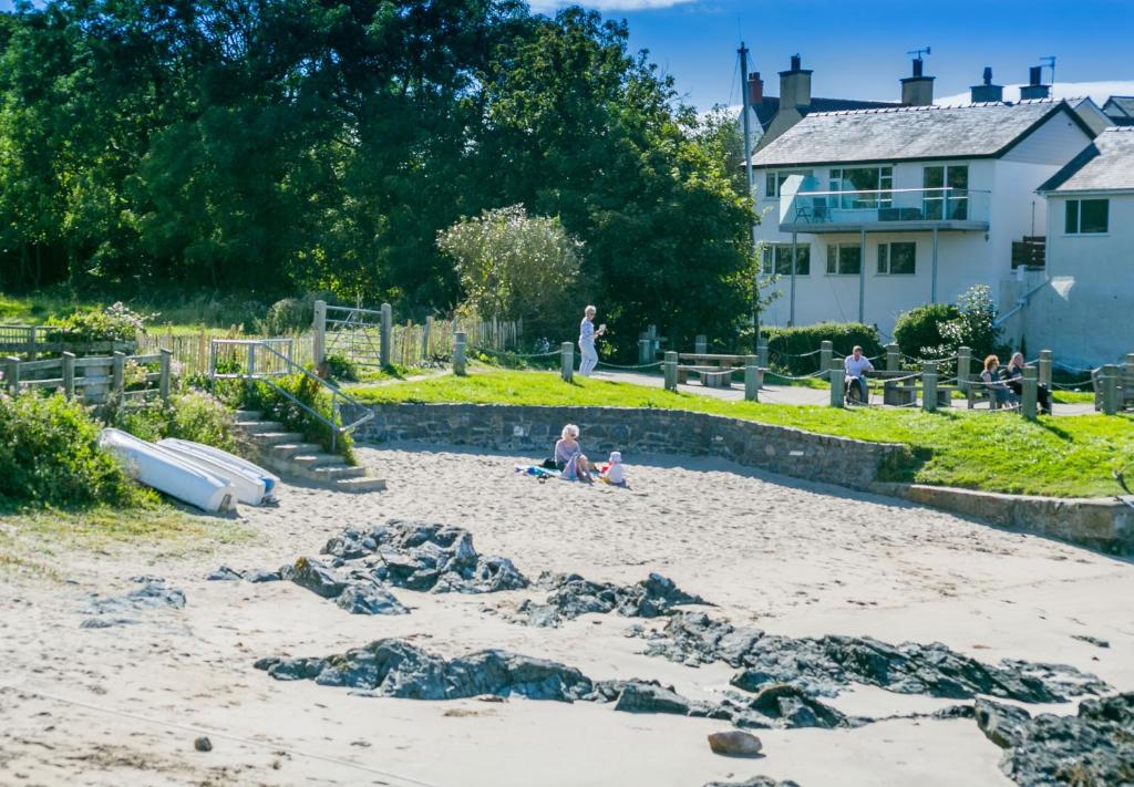 Un uomo seduto sulla sabbia sulla spiaggia di Min y Wygyr a Cemaes Bay