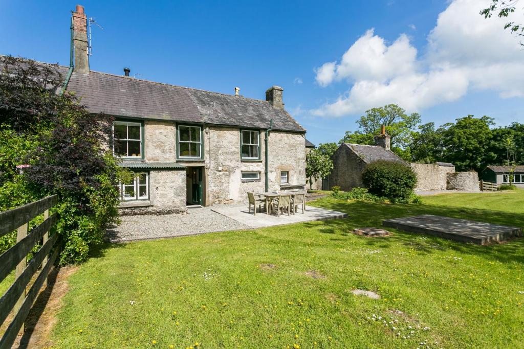 an old stone house with a picnic table in the yard at Plas Lligwy Cottage in Moelfre