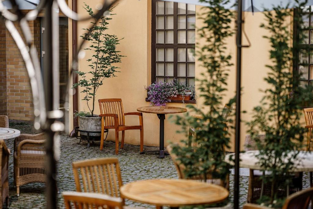 un patio con mesas, sillas y plantas en Euterpe Hotel, en Klaipėda