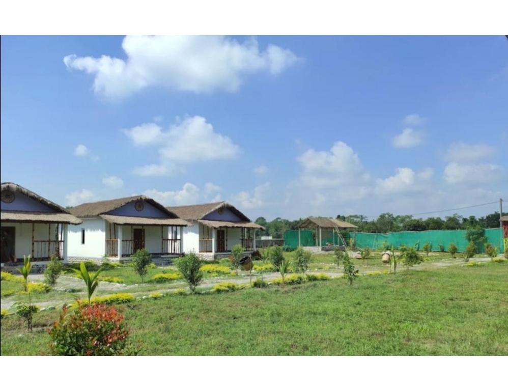 a row of houses in a field with a green fence at Manas View Jungle Resort, Assam in Jyoti Gaon