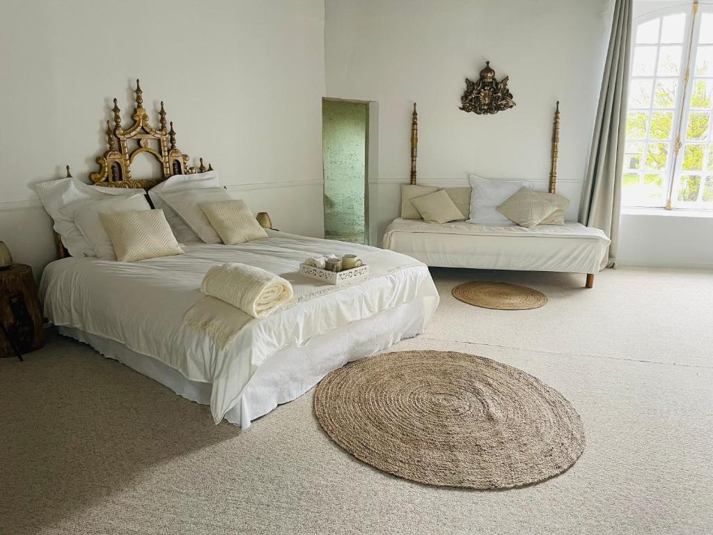 a white bedroom with a large bed and a couch at Le Saint Leonard in Montceaux-lès-Provins