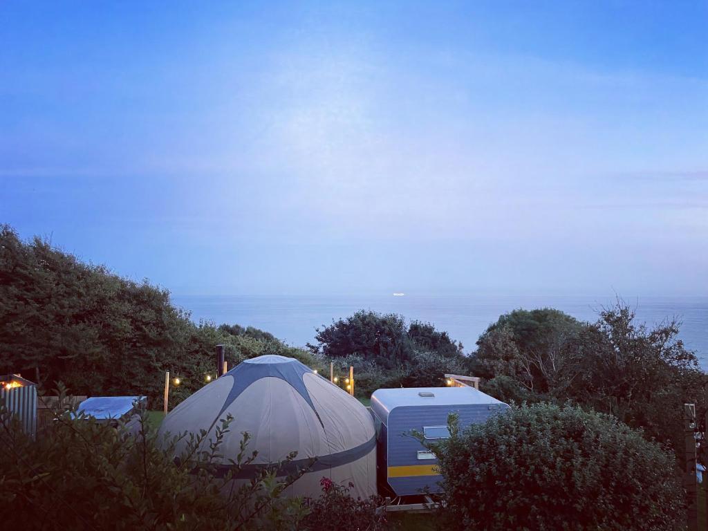 um par de tendas e um campista num quintal em Puckaster Cove Garden Yurt em Niton