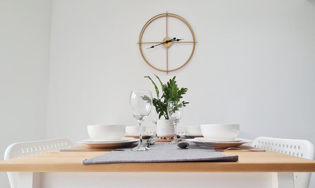 a dining room table with a clock on the wall at Spacious Semi - Off Street Parking - Central Crewe in Crewe