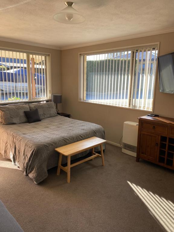 a bedroom with a bed and a table and windows at Riverside Studio in Wanaka