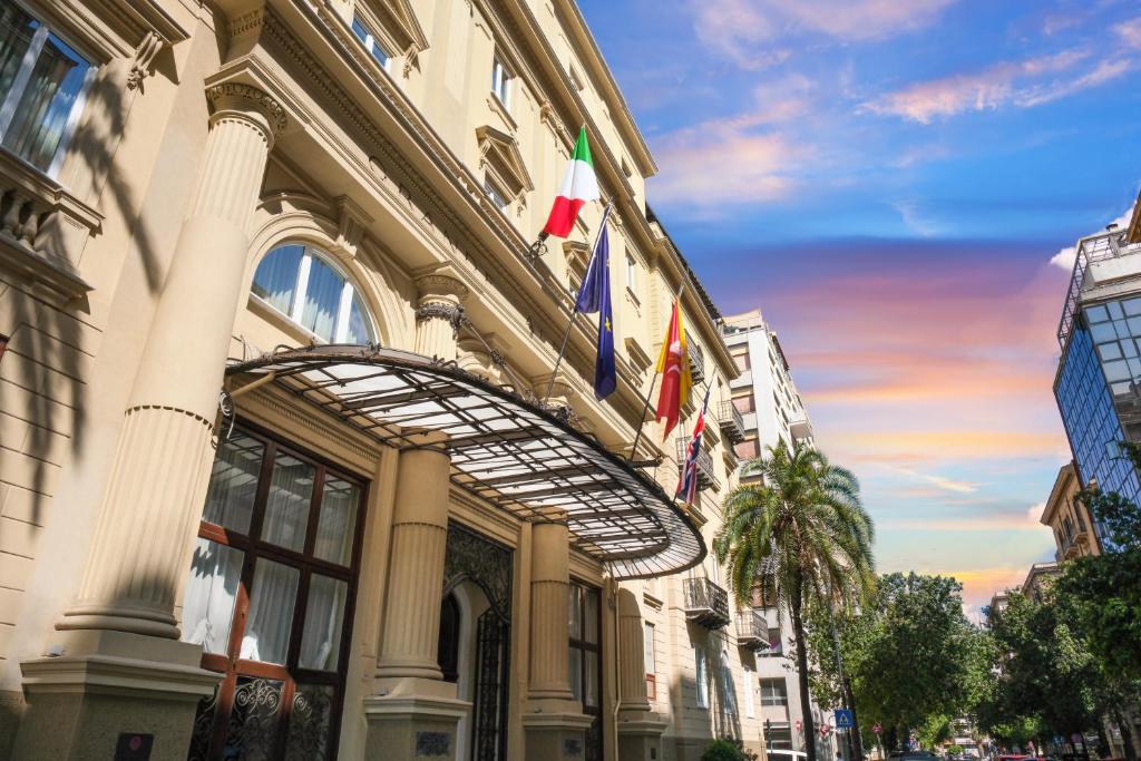 un bâtiment avec des drapeaux sur son côté dans l'établissement Grand Hotel Et Des Palmes, à Palerme