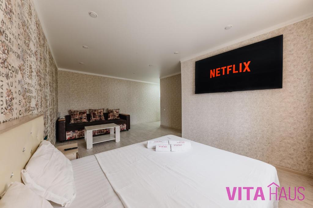 um quarto com uma cama branca e uma televisão na parede em Квартира в центре Лото em Petropavl