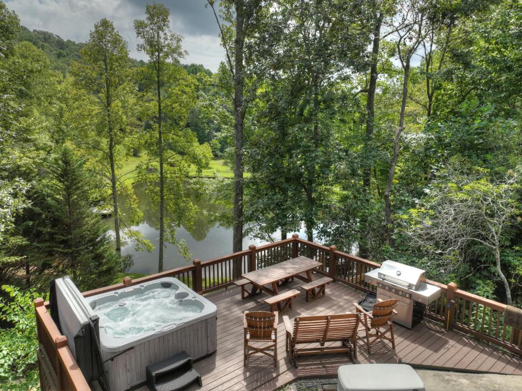 a deck with a hot tub and a picnic table at CaBEARnet Creek Cabin - hot tub, pet friendly, fire pit, outdoor fireplace in Morganton