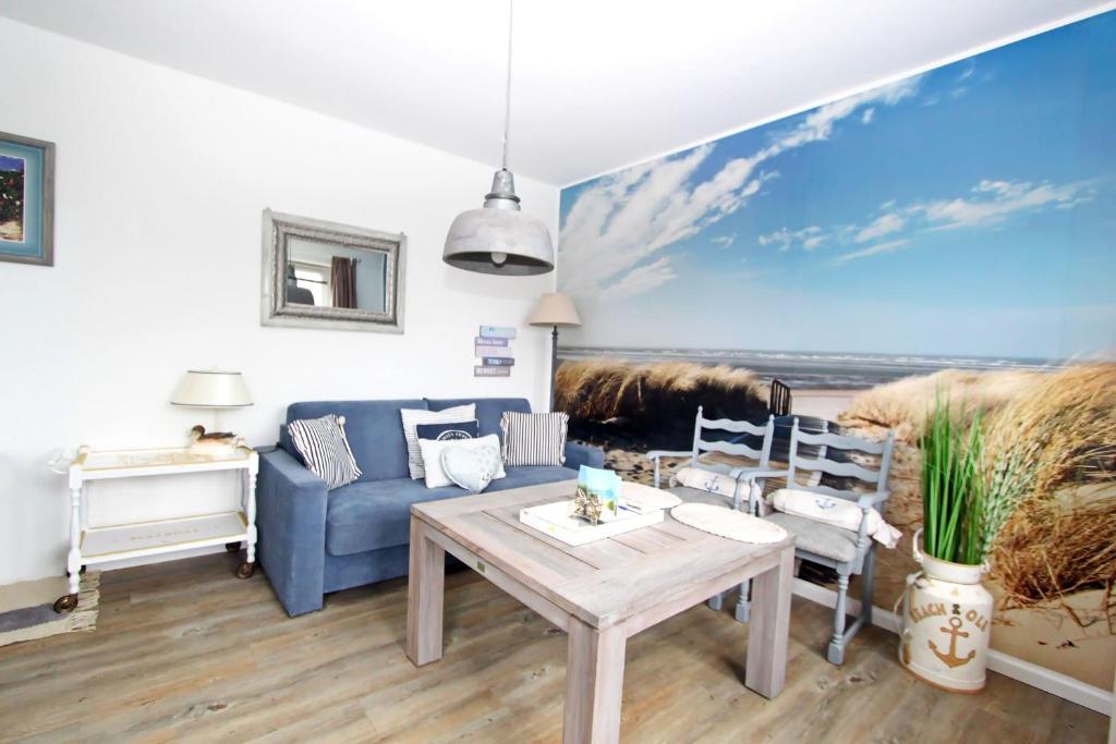 ein Wohnzimmer mit einer blauen Couch und einem Gemälde des Ozeans in der Unterkunft Beach Ole in Hörnum