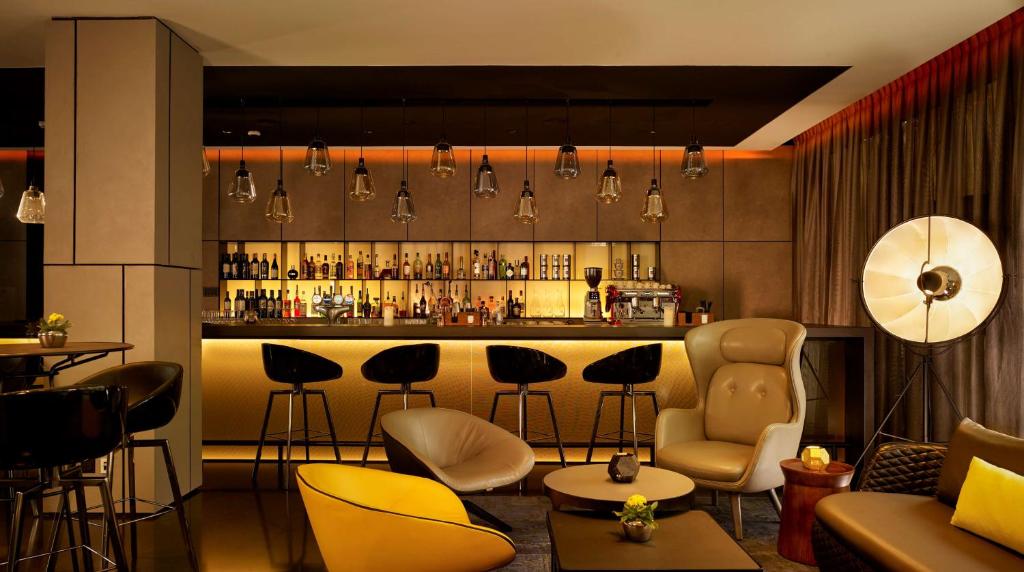 a room with a bar with chairs and a couch at Park Plaza London, Park Royal in London