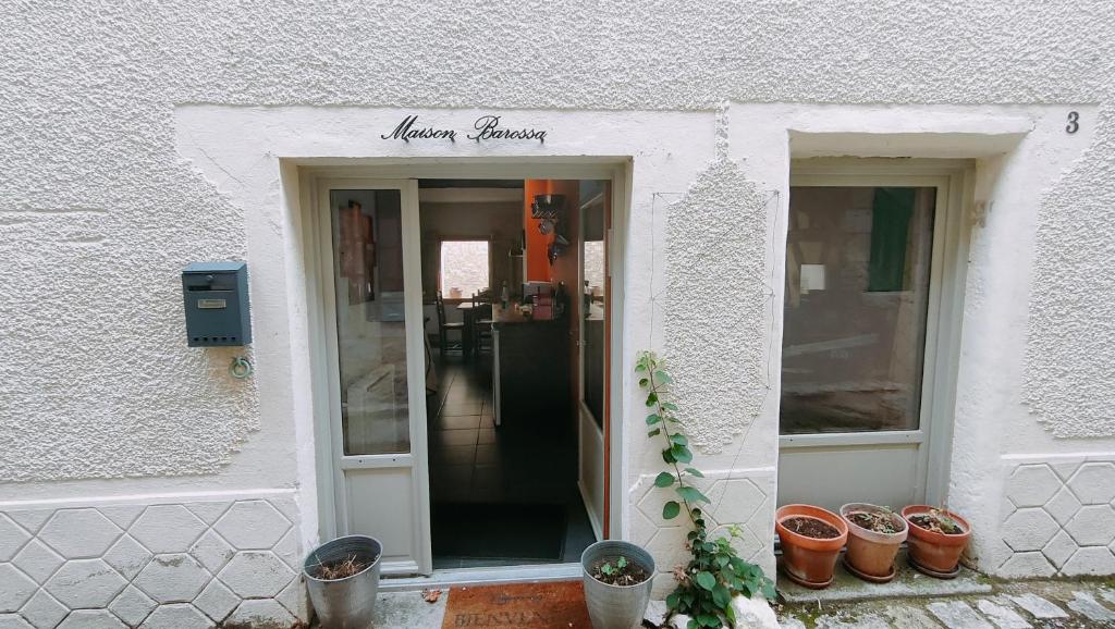 Zugang zu einem weißen Gebäude mit Topfpflanzen in der Unterkunft Maison Barossa Issigeac in Issigeac