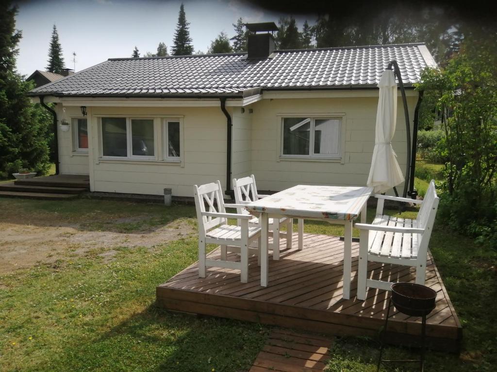 einen Tisch und Stühle auf einer Holzterrasse mit einem Haus in der Unterkunft Sosa's villa. (Free Coffee, BBQ & Garden Fruits) in Turku