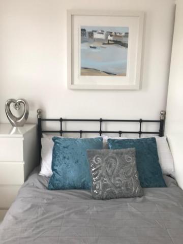 ein Bett mit zwei blauen Kissen und einem Bild an der Wand in der Unterkunft Lovely Studio near Heathrow - 77VFR4 in Cranford