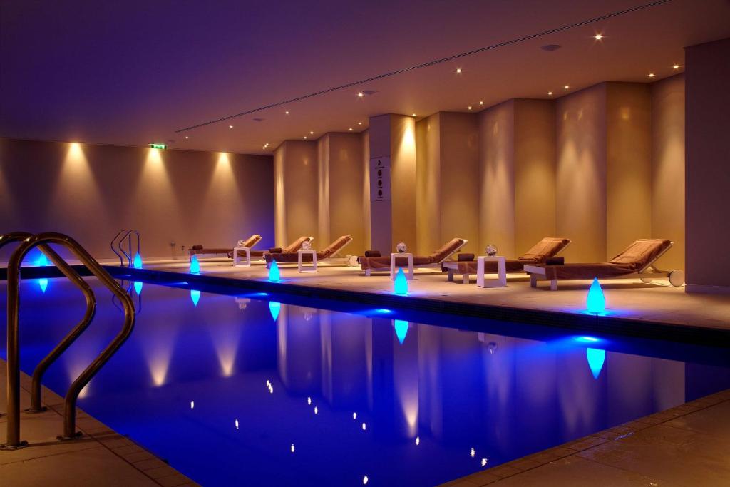 伦敦Park Plaza London Westminster Bridge的一座带椅子和蓝光的游泳池